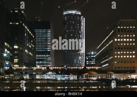 London, Großbritannien - 26 Januar, 2019: DLR-Zug passiert vor moderne Gebäude in Canary Wharf. Canary Wharf ist einer geschäftigen Finanzviertel von London, der oft Stockfoto