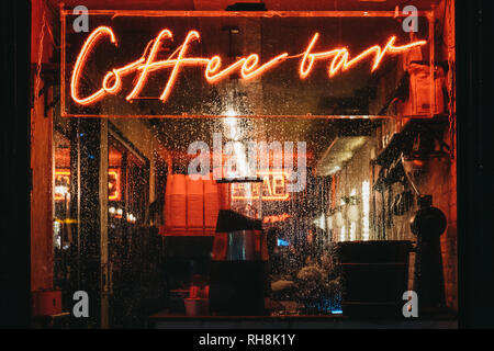 London, Großbritannien - 26 Januar, 2019: Beleuchtete Fenster und Leuchtreklame auf eine Coffee Bar in Canary Wharf an einem regnerischen Abend. Canary Wharf ist ein beschäftigter Finanzielle ein Stockfoto