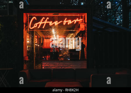 London, Großbritannien - 26 Januar, 2019: Beleuchtete Fenster und Leuchtreklame auf eine Coffee Bar in Canary Wharf an einem regnerischen Abend. Canary Wharf ist ein beschäftigter Finanzielle ein Stockfoto