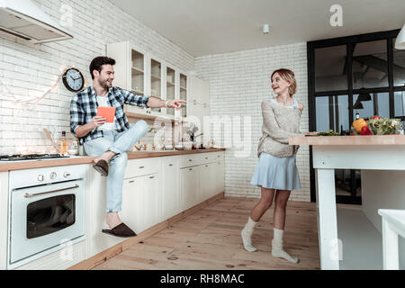 Strahlende junge hübsche Frau mit großen Ohrringen Frühstück vorbereiten Stockfoto