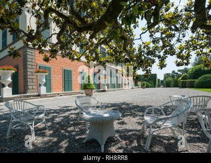 Marlia, Lucca, Italien - 2018, 25. Mai: Tische und Stühle im Schatten eines großen Baumes, auf dem Vorplatz des Villa. Der Villa Reale in Marlia, Lucca, Italien. Stockfoto