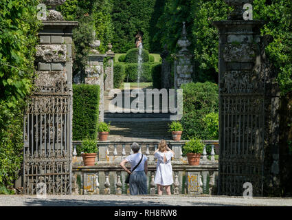 Marlia, Lucca, Italien 2018, 25. Mai: ein Blick auf den Park der Villa Reale. Eine alte Eiserne Tor öffnet sich zum Garten. Touristen bewundern und Fotografieren Stockfoto