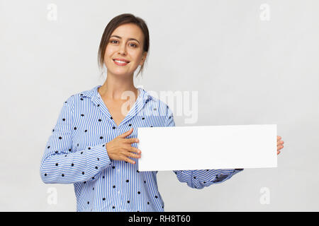 Lächelnd schöne Frau mit leeren Schild, auf weiße Wand isoliert Stockfoto