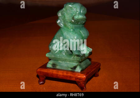 Chinesische Löwe Abbildung aus grüner Jade - auf hölzernen Podest isoliert Stockfoto