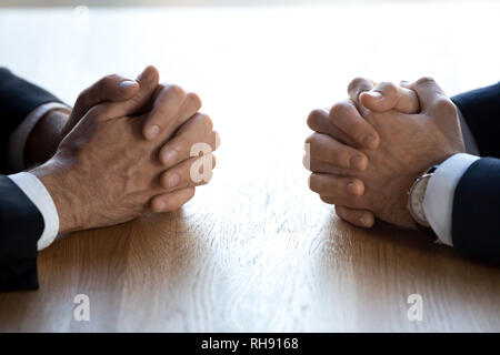 Gefalteten Händen von zwei Geschäftsmänner Verhandlungsführer Gegner gegenüber am Tisch Stockfoto