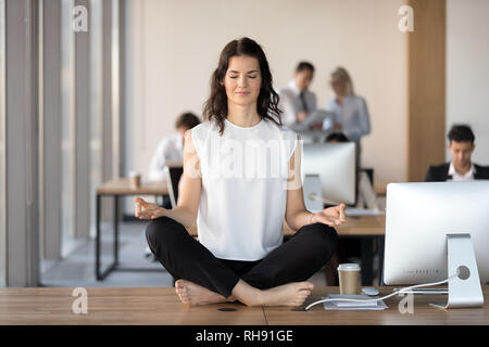Ruhige junge geschäftsfrau Yoga Übung am Schreibtisch Stockfoto