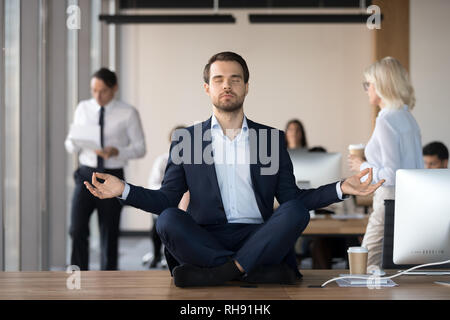 Ruhe Geschäftsmann in Anzug meditieren im Büro am Schreibtisch Stockfoto