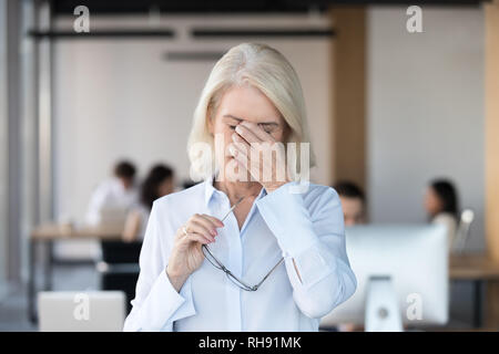 Müde müde älterer weiblicher Angestellter, die Gläser Gefühl Überanstrengung der Augen Stockfoto