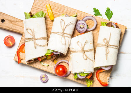 Burritos Tortilla Wraps mit Rindfleisch und Gemüse auf weiße Holztisch. Traditionelle lateinamerikanische Küche. Ansicht von oben. Stockfoto