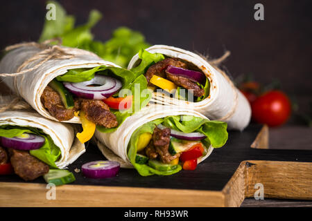Burritos Tortilla Wraps mit Rindfleisch und Gemüse auf Holz Schneidebrett. Traditionelle lateinamerikanische Küche. Stockfoto
