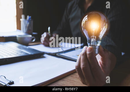 Hand der männlichen Holding eine Glühbirne und Schreiben für Idee und Konzeption. Stockfoto