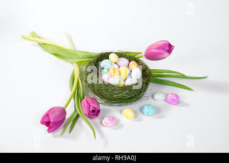 Pastellfarben Easter egg candy grün Vogelnest mit rosa Tulpen isoliert auf weißem Stockfoto