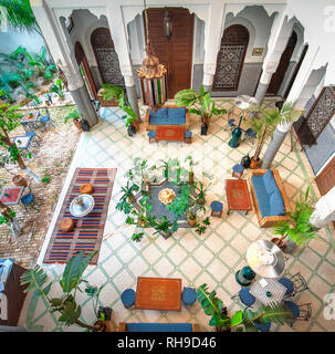 Innenhof mit gefliesten Wänden und Fußboden aus Mosaik. Traditionelle verzierten und farbenfrohe Arabesque wand Schnitzereien über einem Torbogen in den marokkanischen Riad. Stockfoto