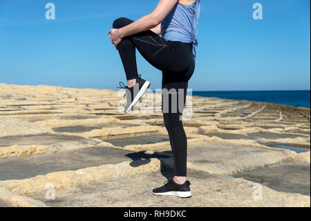 Nahaufnahme einer Frau dabei ein Bein strecken warm, draußen in der Sonne Stockfoto