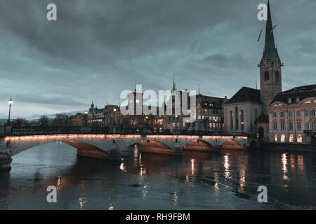 Blick auf die Altstadt von Zürich am Fluss Limmat mit Fraumünster Kirche in der Abenddämmerung Stockfoto