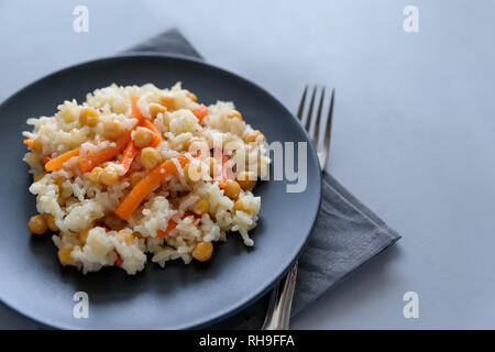 Leckere vegetarische Pilav mit Reis, Karotte und Kichererbsen auf grau Holz- Hintergrund. Kopieren Sie Platz. Ansicht von oben. Selektiver Fokus Stockfoto