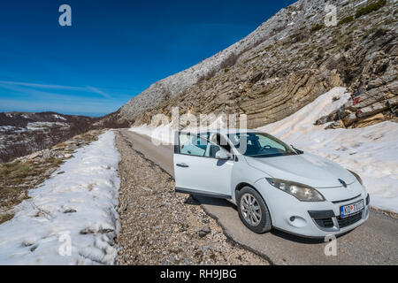 Nationalpark Lovcen, Montenegro - April 2018: Die weissen Pkw warten auf der Straße der kleinen Erdrutsch im Winter zu gelöscht werden. Stockfoto