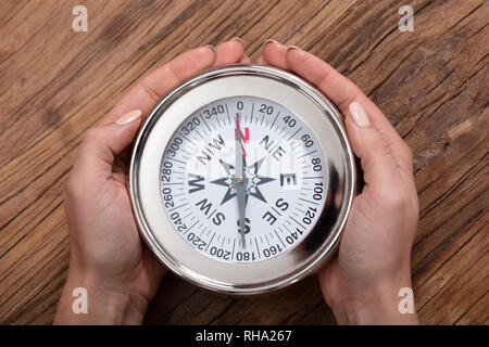 Ansicht von der Frau Hand mit Kompass auf hölzernen Schreibtisch Stockfoto