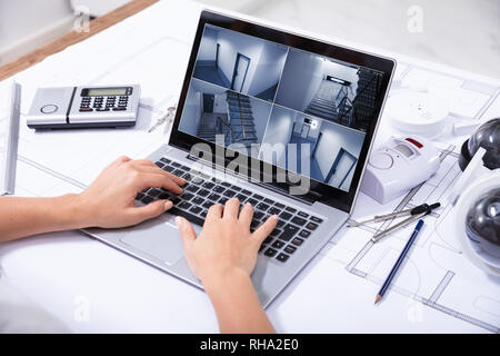 Nahaufnahme einer Frau Monitoring Home Überwachungskameras auf Laptop über den blauen Drucken Stockfoto