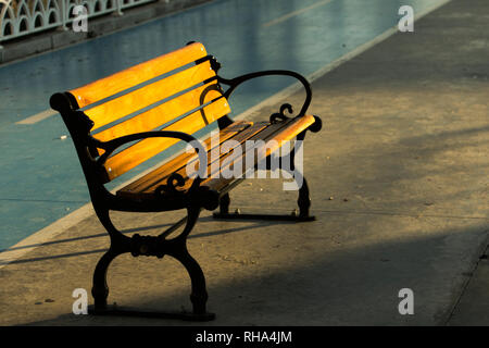 Morgen Licht auf eine Guss- und Holz- Street Bank mit Fahrrad Lane im Hintergrund. Stockfoto