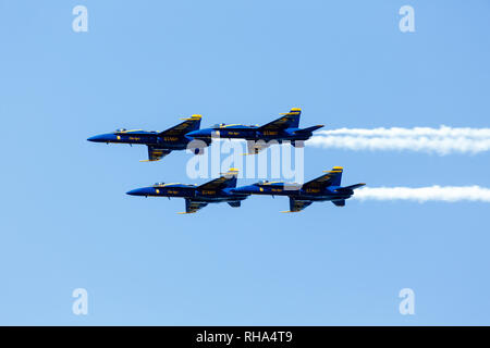 Die Blue Angels, die Flugdemonstrationsschwadron der US Navy, führen ein Flugmanöver durch, wobei sie weiße Rauchspuren vor einem klaren blauen Himmel hinterlassen und ihre Präzision und Geschicklichkeit unter Beweis stellen. Stockfoto