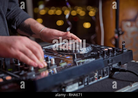 Dj-Mixe der Spur in der Diskothek an der Partei. Kopfhörer im Vordergrund und DJ Hände in Bewegung. Club Party DJ spielt live auf der Bühne im Nachtclub. Stockfoto