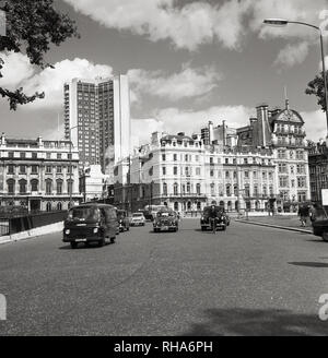 1960er, London, Fahrzeuge der damaligen Zeit auf dem Gipfel des Hyde Park, in der Nähe von Marble Arch, zeigt ein modernes Hochhaus, das sich über den traditionellen Gebäuden der Stadt erhebt. Die Entwicklung in dieser Ära hoher Büroblöcke aus vorgegossenem Beton sollte die Skyline Londons für immer verändern. Stockfoto