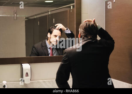 Besorgt Hispanic Mann auf Haarlinie in Büro sanitäre Einrichtungen Stockfoto