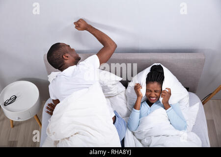 Eine Ansicht von Paar liegend auf Bett gestört durch Lärm Stockfoto