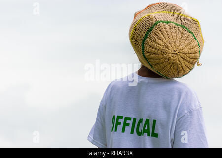 Schwarz erwachsenen männlichen Rastafari mit Dreadlocks in Gestrickt tam tragen weiße t-shirt markiert Beamter an sportlichen Ereignis Stockfoto