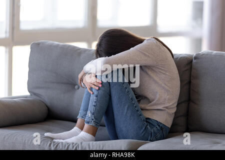 Niedergedrücktes jugendlich Mädchen sitzen auf der Couch alleine Angstgefühle schämen Stockfoto