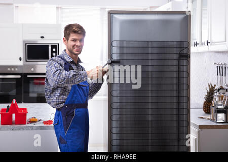 Soldaten in insgesamt Arbeiten am Kühlschrank mit Schraubenschlüssel in der Küche Stockfoto