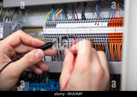 Nahaufnahme eines männlichen Elektriker Prüfung Sicherungskasten mit Multimeter Stockfoto