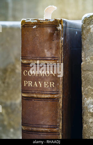 Nahaufnahme von einem alten Gebet in Leder gebundenes Buch auf einem Stein Regal in einer alten Kirche Stockfoto