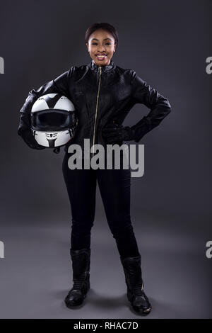 Schwarze weibliche Motorrad Biker oder Rennfahrer oder Stuntwoman aus Leder racing Suit und halten einen Schutzhelm. Sie steht sicher Stockfoto