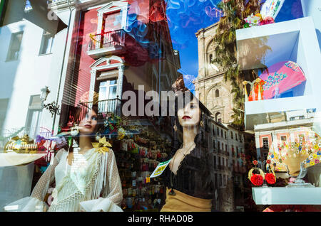 Granada, Andalusien, Spanien: Fenster mit weiblichen Schaufensterpuppen in Rocio Flamenco Mode und Reflexionen von der Kathedrale und dem historischen Granada cent Stockfoto