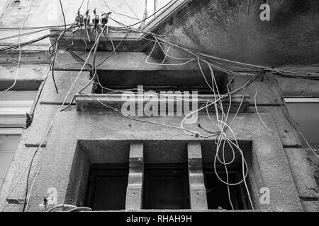 Chaotische Kabel Management der installierten elektrischen und optischen Kabeln am Wohnhaus in Sofia, Bulgarien. Schwarz/Weiß-Kontrast Stockfoto