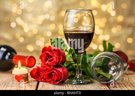 Valentinstag Konzept. Zwei Gläser Wein, rote Rosen, Wein Flasche und brennende Kerze auf einem rustikalen Holztisch. Stockfoto