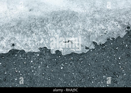 Eisschmelze auf Pflaster oder schwarzen Asphalt im Frühjahr Stockfoto