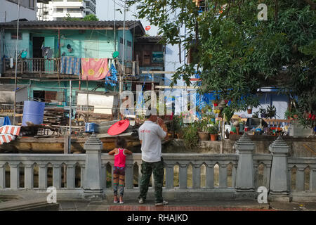 Ein Mann und sein Sohn ein Slum-Szene neben einem Klong (Kanal) in Bangkok, Thailand Stockfoto