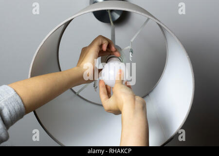 Frau Austausch der Glühbirne zu Hause. Strom sparen LED-Lampe wechseln Stockfoto