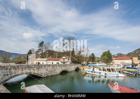 Virpazar, Montenegro - April 2018: Alte Bogenbrücke und verankerte Touristen Boote in Virpazar Stadt Stockfoto