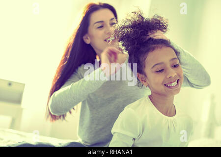 Pflege verantwortlich Mom bürsten Haare ihrer mulatto Tochter. Stockfoto