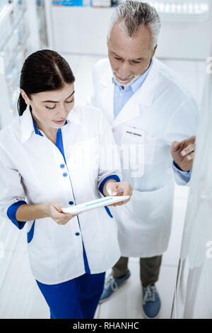 Zwei Apotheker in weißen Kitteln diskutieren Um eine Apotheke Stockfoto