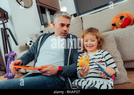 Die hübsche kleine Rothaarige Mädchen in einem gestreiften Pullover spielen mit einem gelben Spielzeug Stockfoto