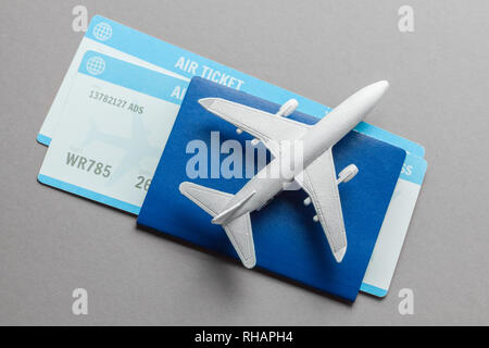 Tickets für Flugzeug und Reisepass mit Modell der Passagiermaschine auf grauem Hintergrund. Stockfoto