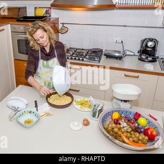 Süße Hausfrau bereitet einen Kuchen in einem unordentlichen Küche Stockfoto