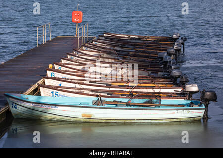 Ravensthorpe, Northants, UK - 2. Februar 2019: Boote kleine Holz- Angler' mit Außenbordmotoren sind gegen einen schwimmsteg an einem Behälter vertäut. Stockfoto