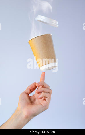 Eine Tasse mit heißem Kaffee und eine Wolke von Dampf Salden auf der Fingerspitze. Frei schwebende Schale aus Kunststoff Deckel. Kaffeepause Konzept. Leeren platz für Stockfoto