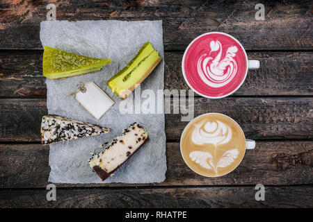 Ansicht von oben Latte Art mit zwei Arten von käsekuchen auf Holztisch, Coffee shop Hintergrund. Mit der Kopie Platz für ihr Logo. Stockfoto